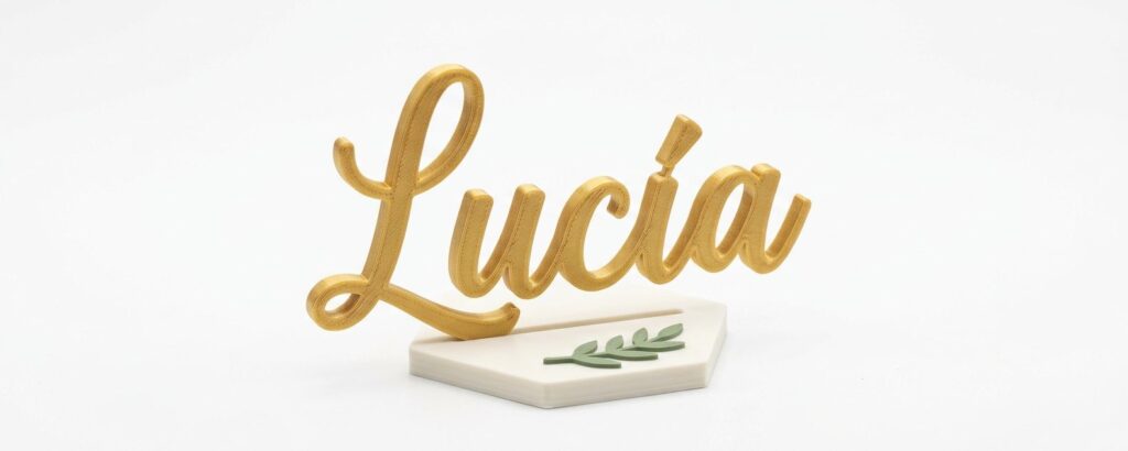 Marcasitio de boda impreso en 3D con el nombre Lucía en dorado sobre base hexagonal